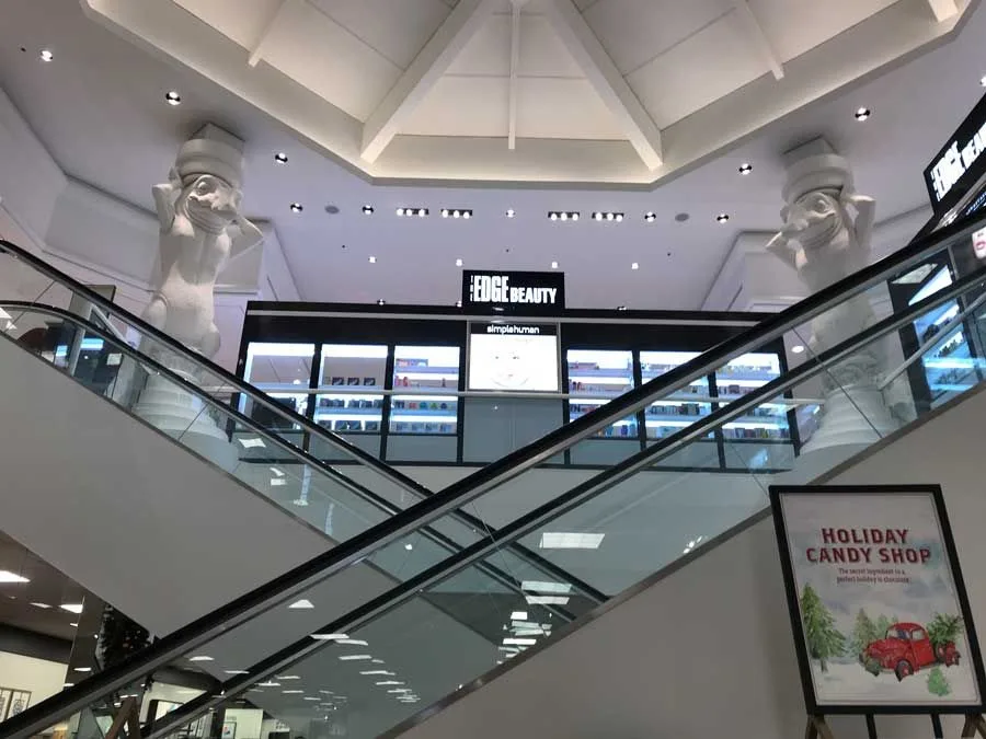 An escalator in a mall with a sign that says holiday candy salad